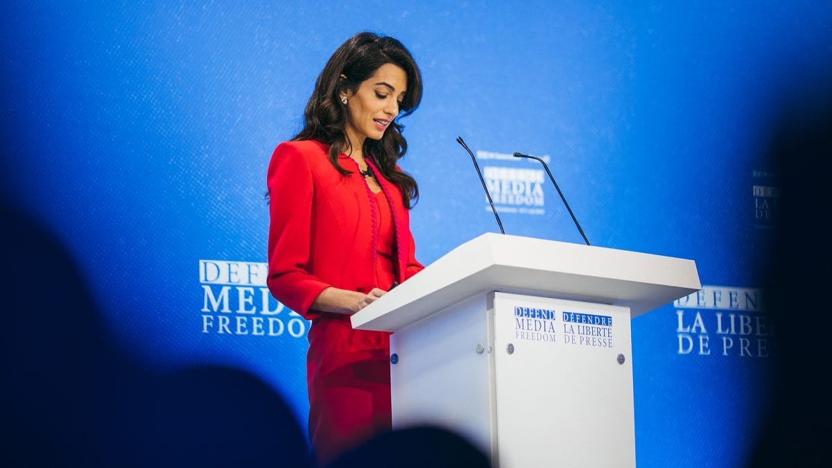 Speaker wearing red at the podium at the Global Conference for Media Freedom