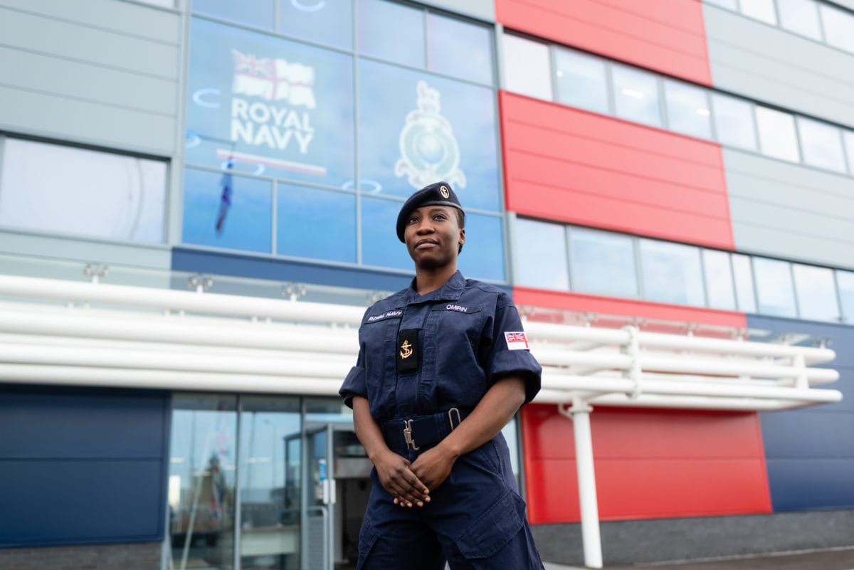 A Royal Naval cadet stands in front of a building
