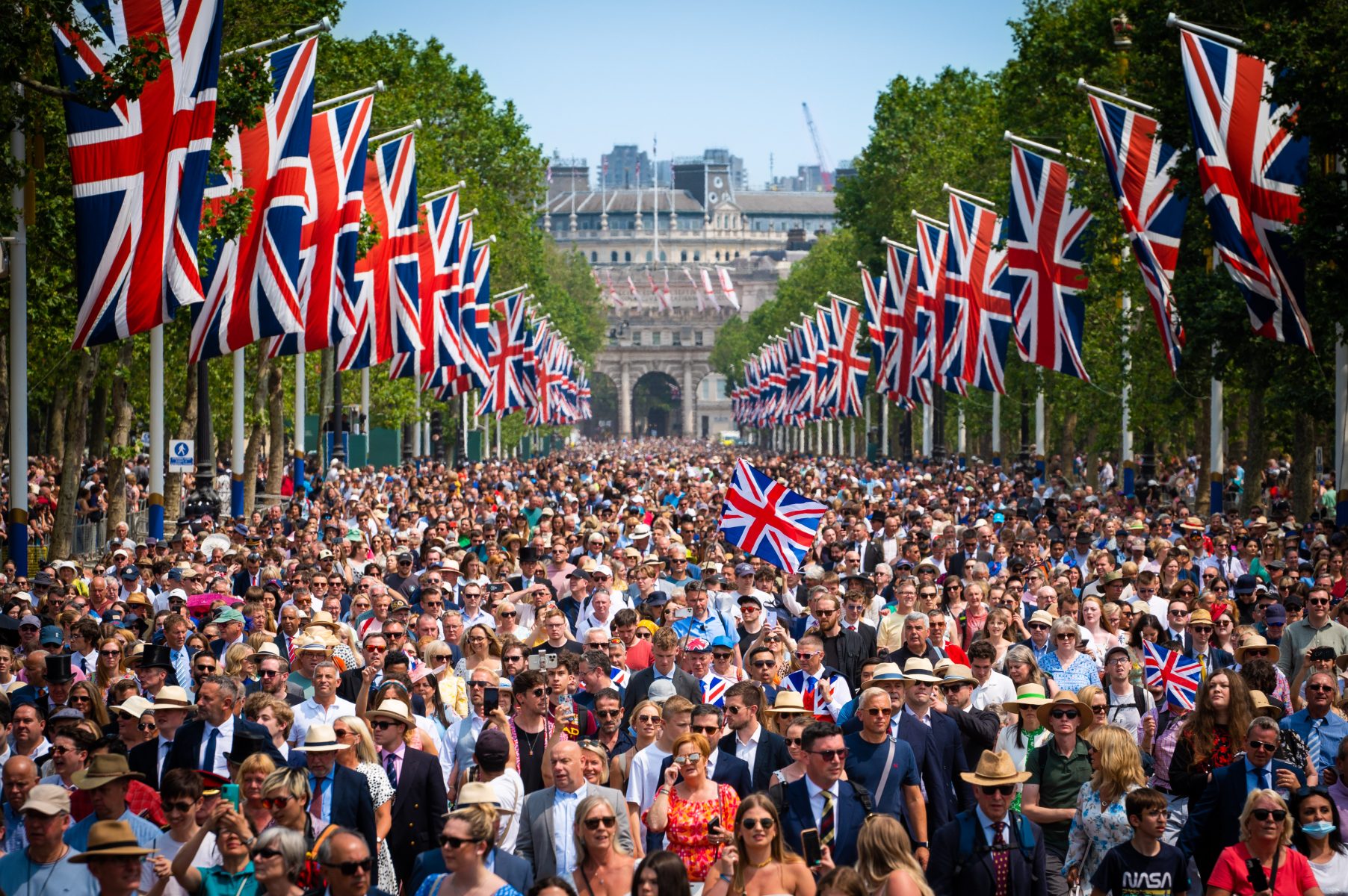 Image of a large crowd in summer flanked by UK flags