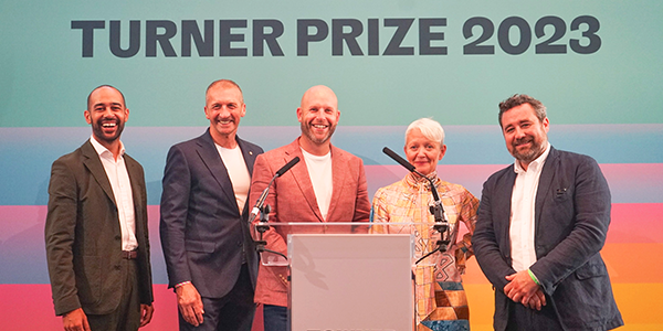 Members of Identity standing in front of a podium at the Turner Prize
