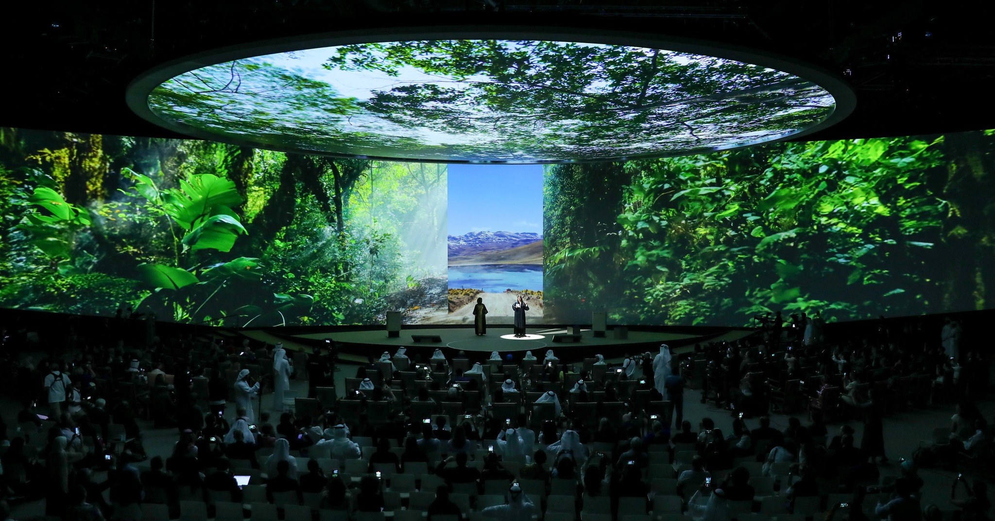 Immersive rainforest projections surround speakers and delegates at the Reaching the Last Mile Forum during COP28 in Dubai.