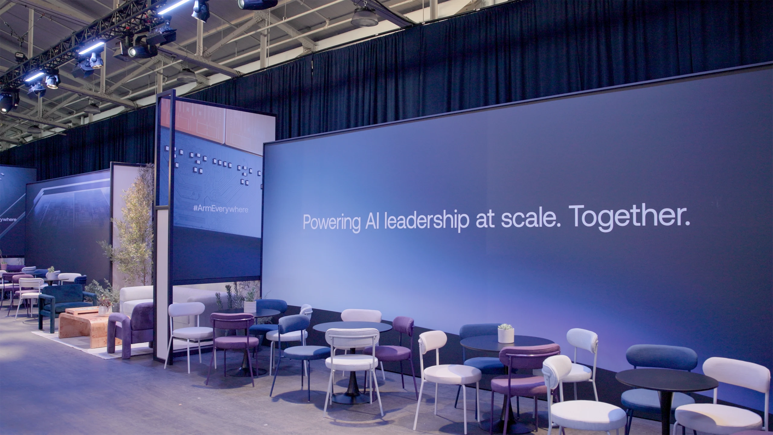 Arm Everywhere networking lounge with blue and purple seating beneath a large Powering AI Leadership at Scale display