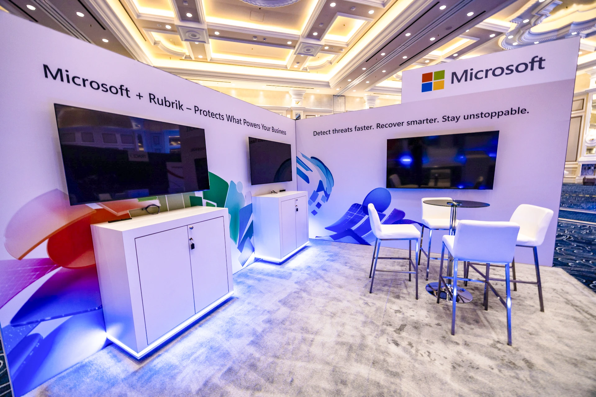 Microsoft-branded partner stand within the Rubrik Forward 2026 brand experience, with digital screens and seating