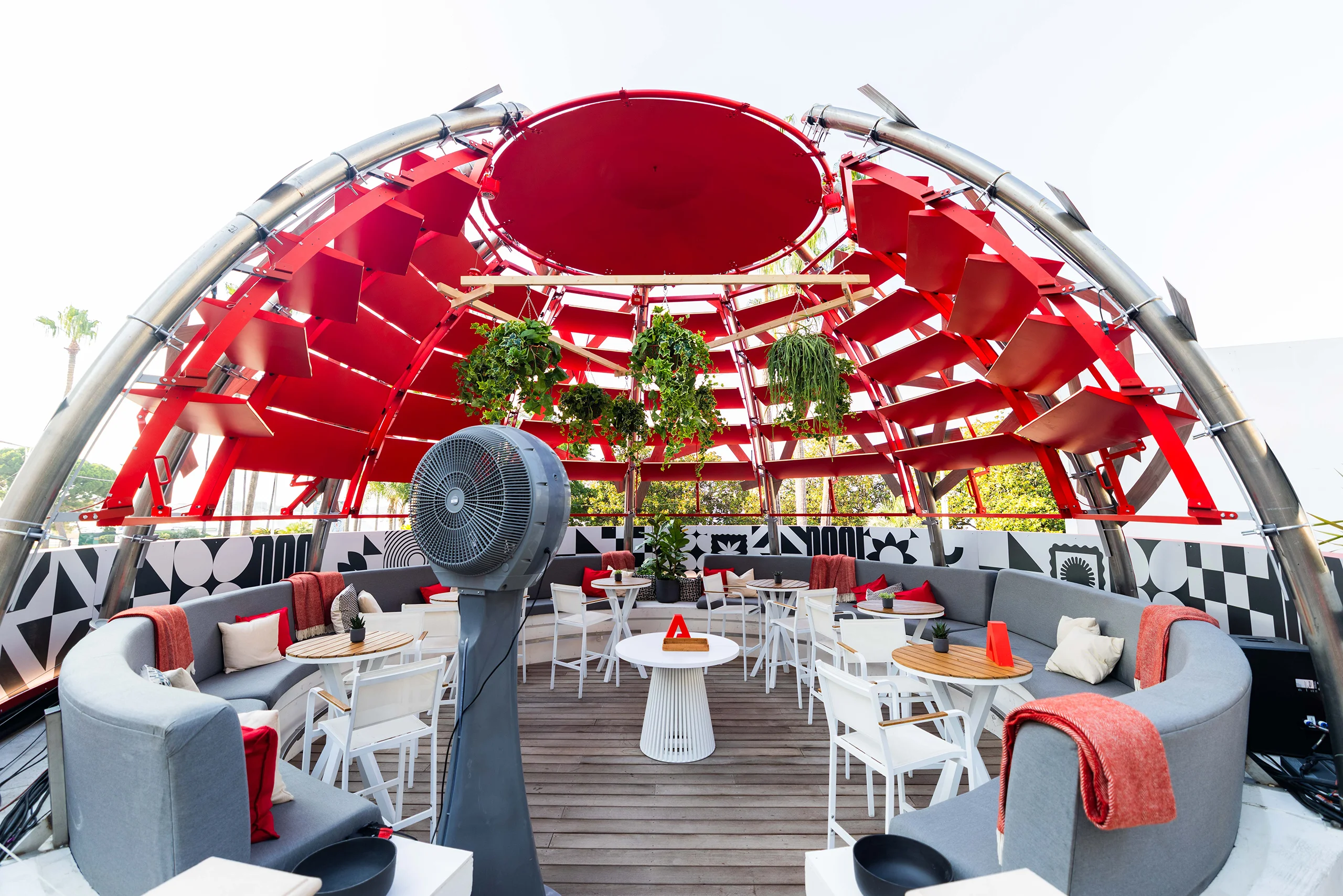 Adobe Cannes Lions outdoor lounge with a red canopy, curved seating and large cooling fan