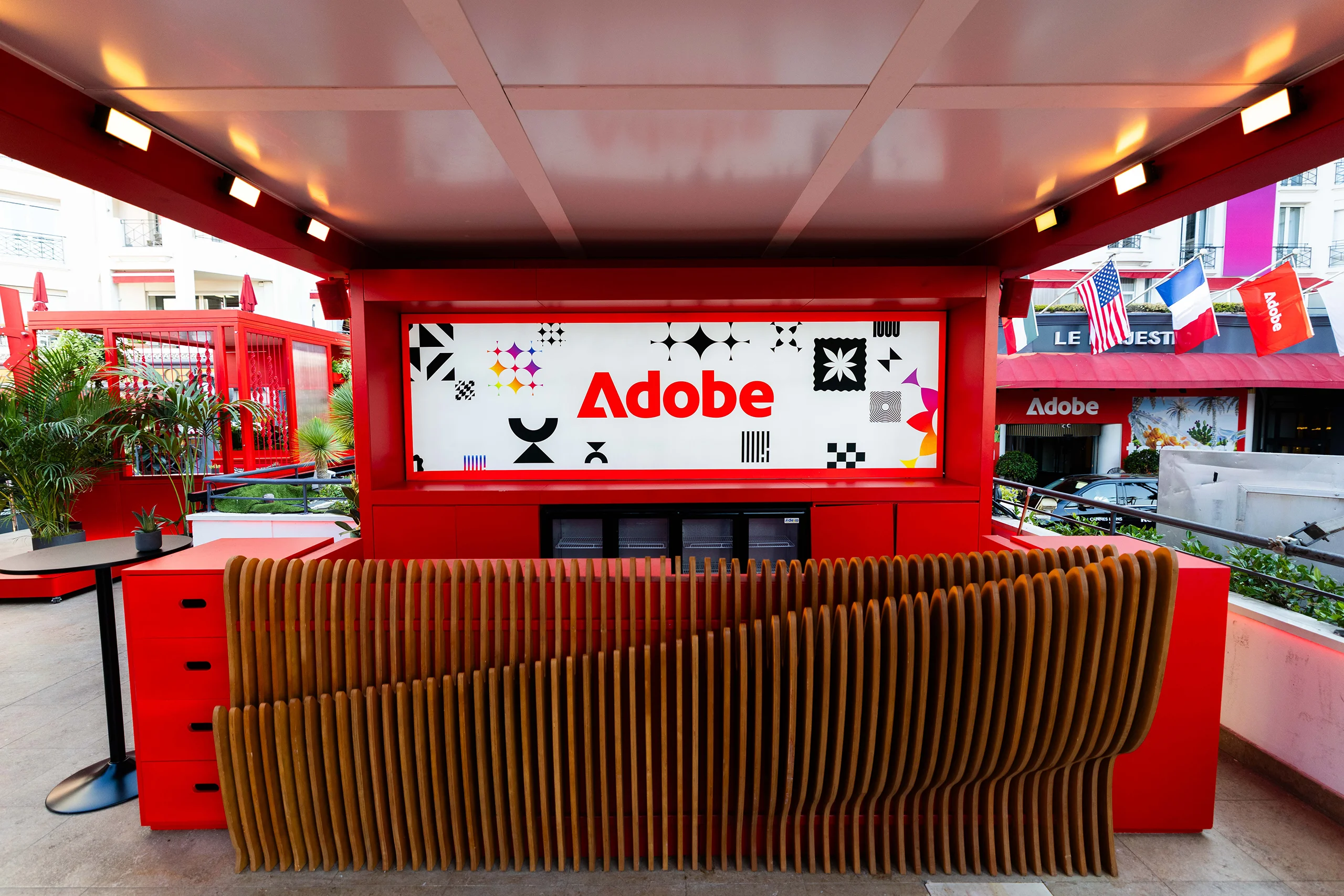 Adobe branded outdoor bar with a sculptural wooden counter and colourful graphic display