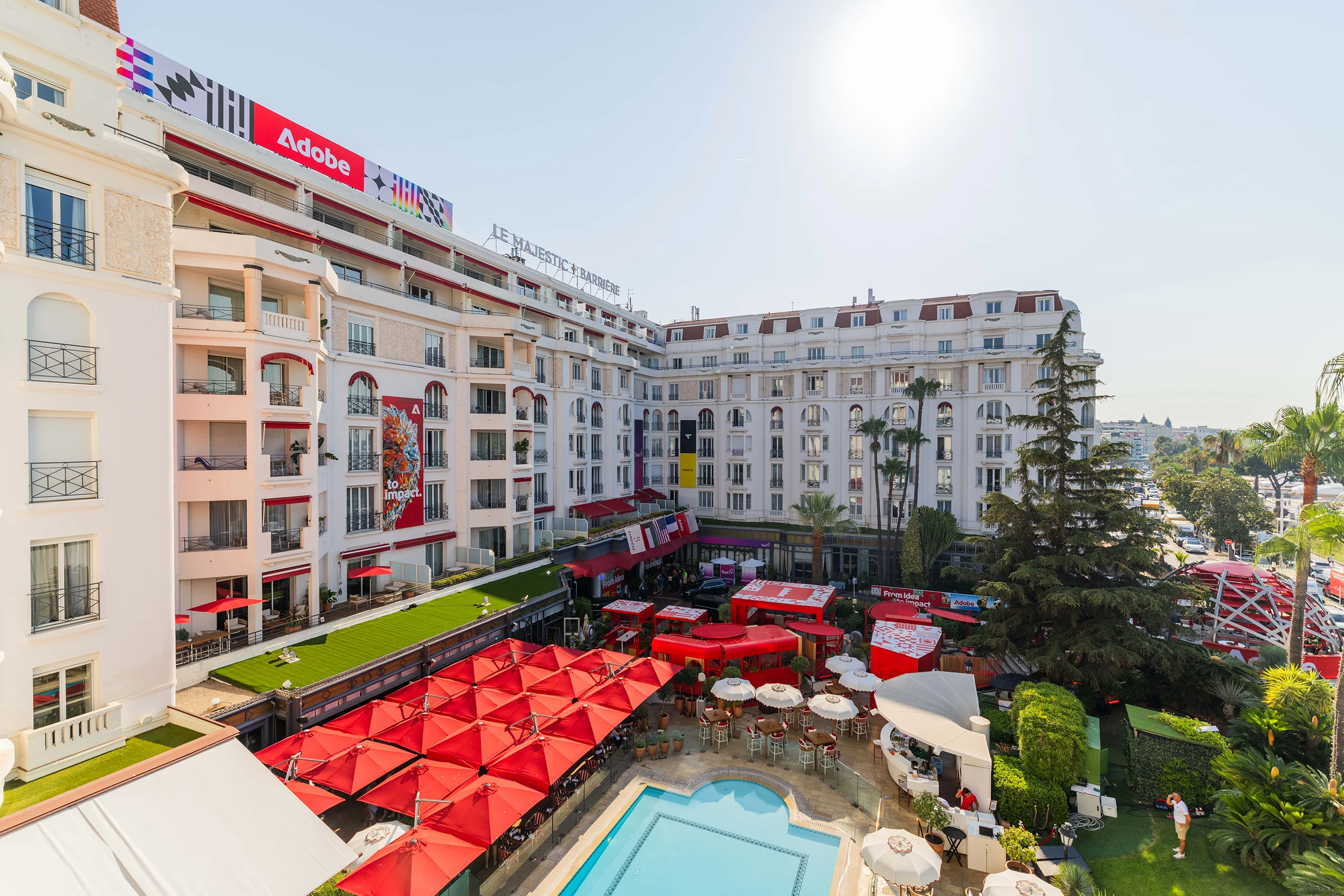 Adobe brand activation venue at Cannes Lions, with red umbrellas and an outdoor swimming pool
