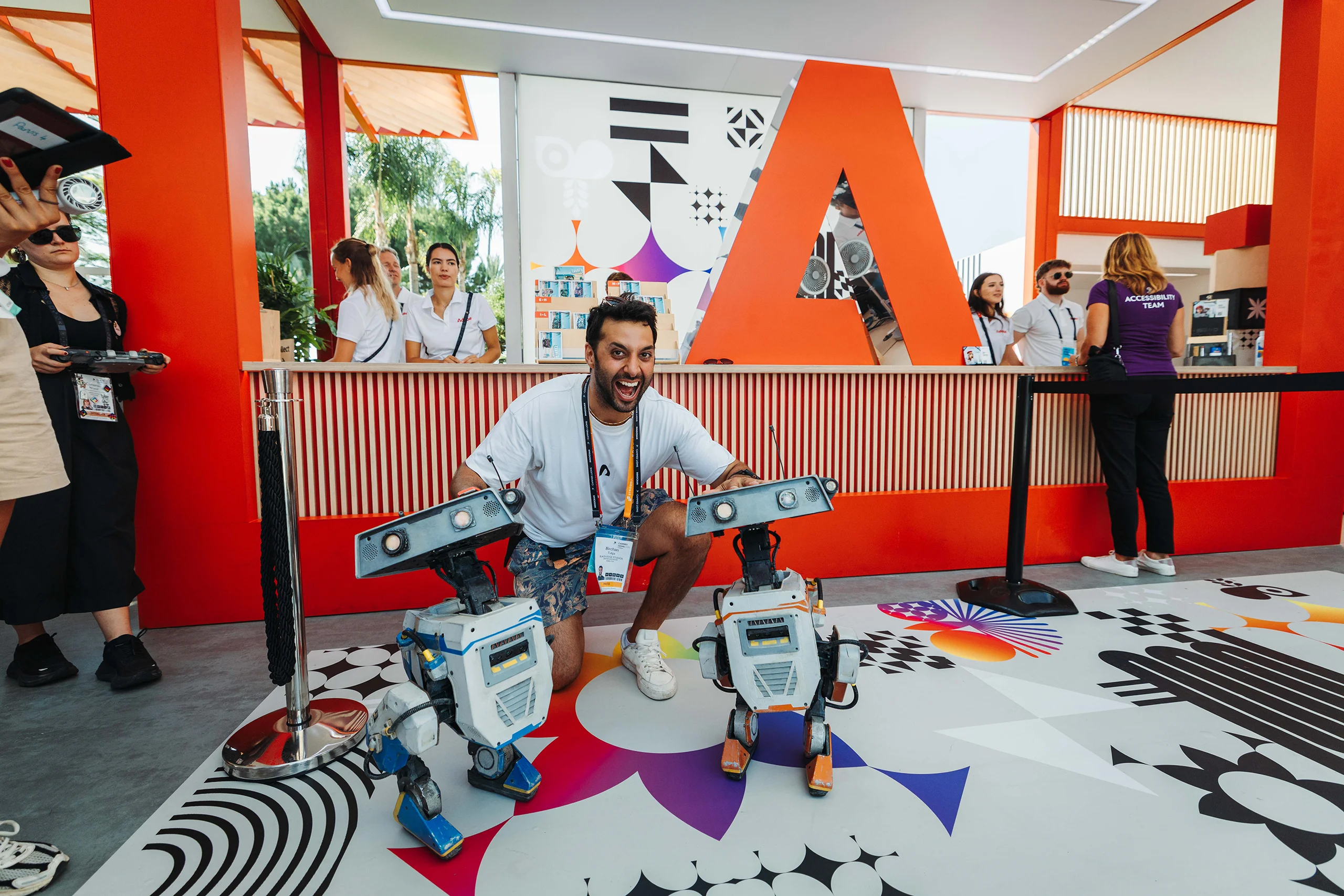 Guest posing with two small robots at Adobe's Cannes Lions activation